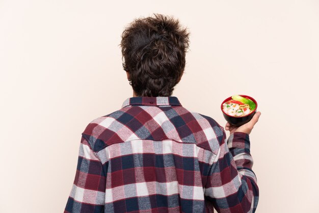 写真 バックポジションで麺のボウルを保持している男