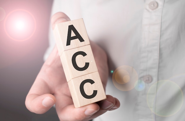 Man holding acc word on wooden cube.