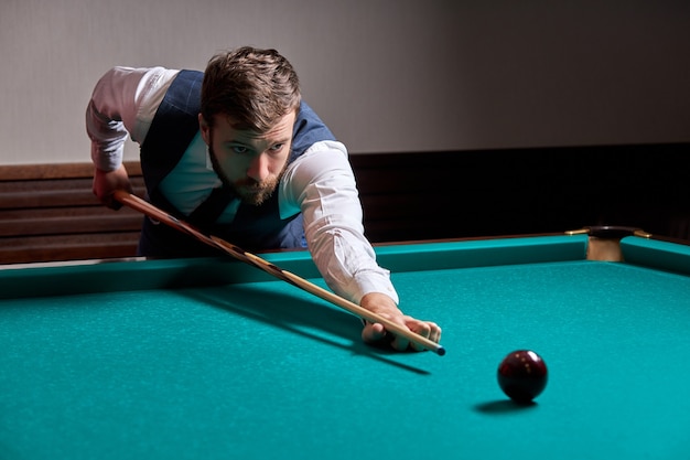 Man holding arm on billiard table, playing snooker game or\
preparing aiming to shoot pool balls. sport game snooker\
billiards