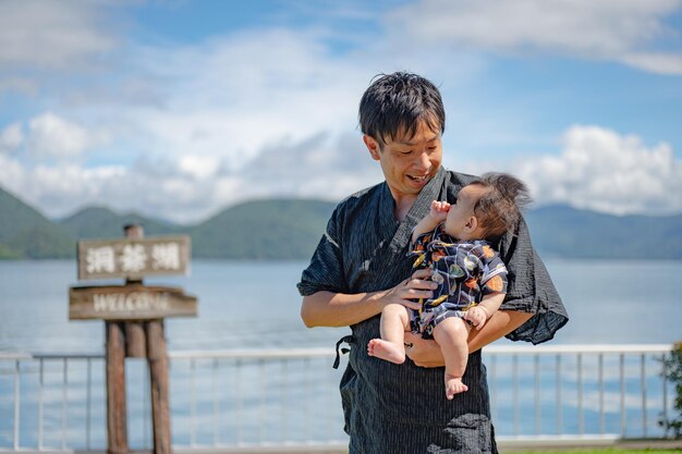 A man holding a baby in front of a lake