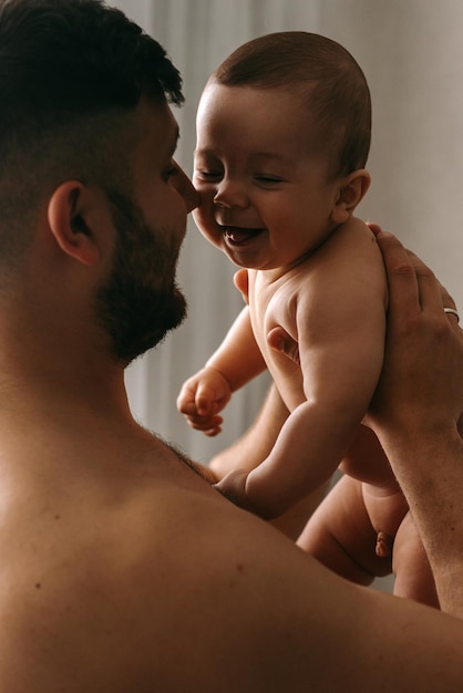 赤ちゃんを抱いてカメラに向かって微笑む男性