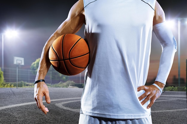 Мужчина держит баскетбольный мяч на баскетбольной площадке