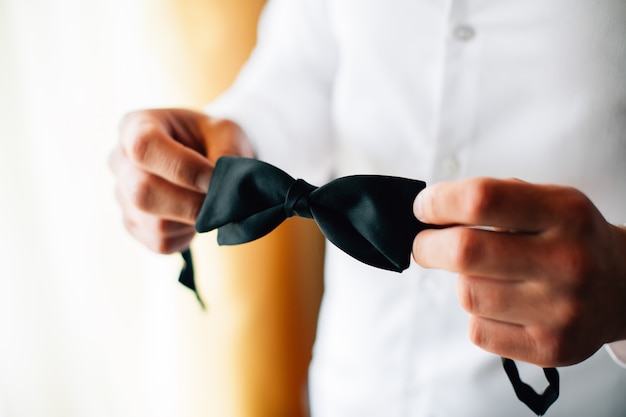 Man holding black bow tie in his hands