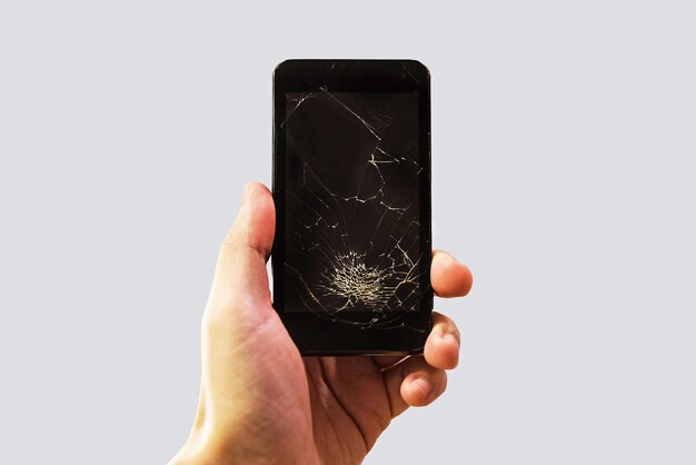 A man holding a black phone with a black broken glass on the screen Cracked smartphone in hand holding