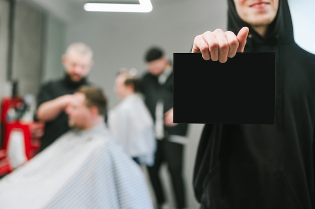 Man holding blank black card, focus on blank space on barbershop