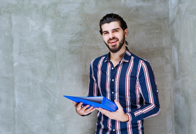 Man holding a blue report folder and smiling.