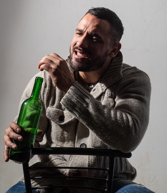 Photo man holding a bottle on studio background brutal attractive bearded biker happy guy with beard drink