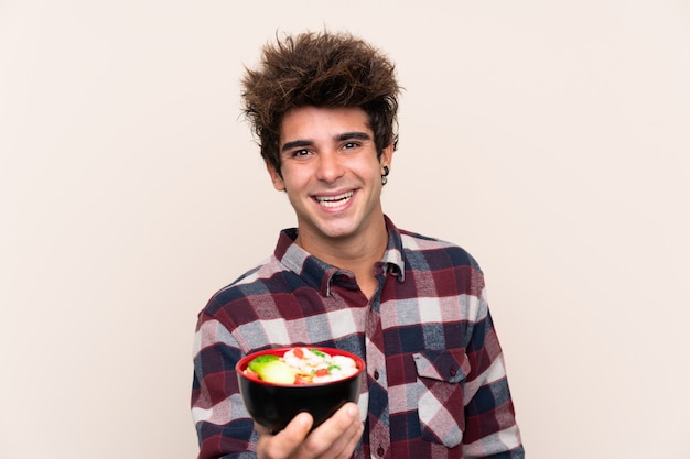 Man holding a bowl full of noodles with happy expression