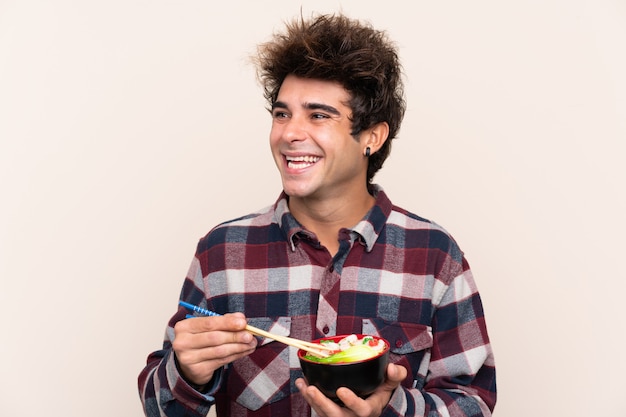 Man holding a bowl full of noodles