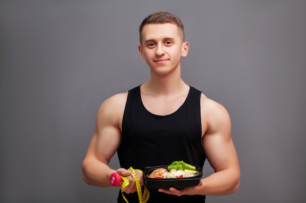 Uomo che tiene una scatola piena di alimenti ricchi di proteine per l'alimentazione sportiva