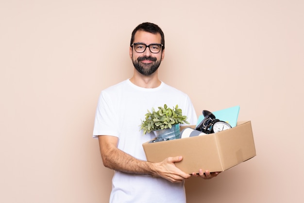 Man holding a box and moving in new home over isolated background with glasses and happy