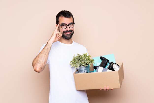 Man holding a box and moving in new home over isolated background with glasses and smiling