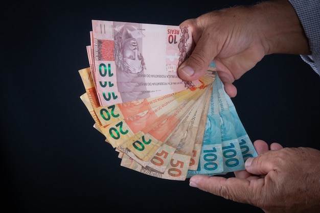 Man holding Brazilian money banknotes