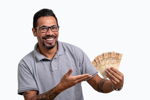 man holding Brazilian money, smiling, wears glasses