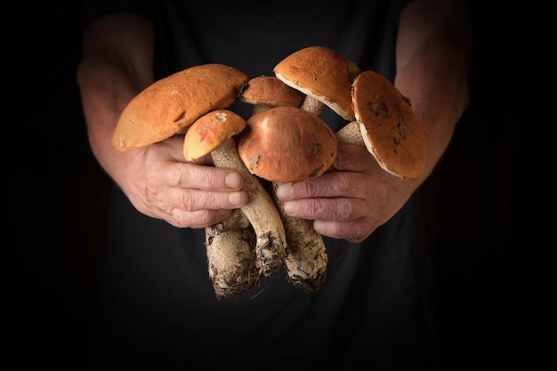 Foto uomo con cappello marrone boletus in mano in stile rustico