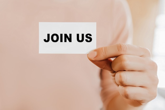 Man holding a business card with Join Us