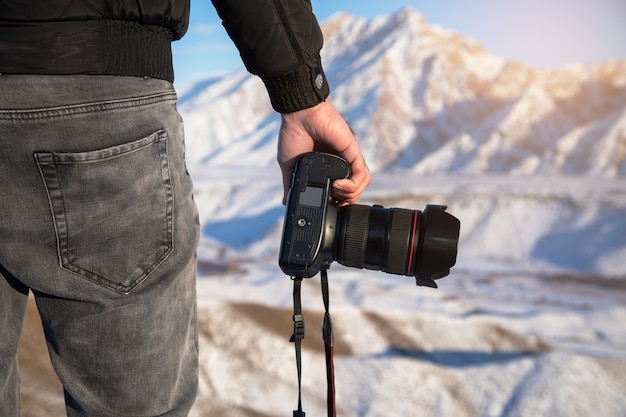 Uomo che tiene la fotocamera in montagna innevata in inverno