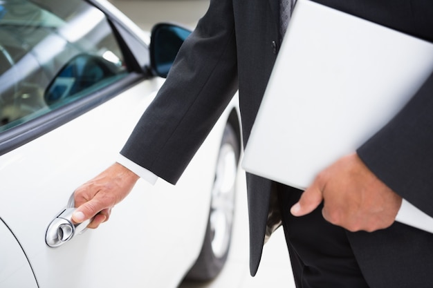 Man holding a car door handles while holding clipboard