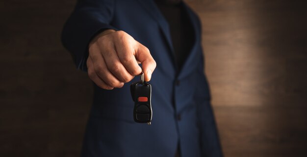 木製の背景に車のキーを保持している男