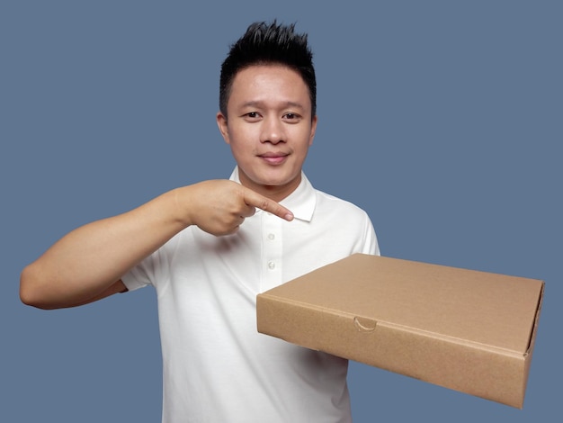 Мужчина держит картонную коробку и указывает изолированным на простом фоне