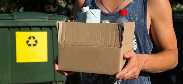 Man holding a cardboard box with garbage