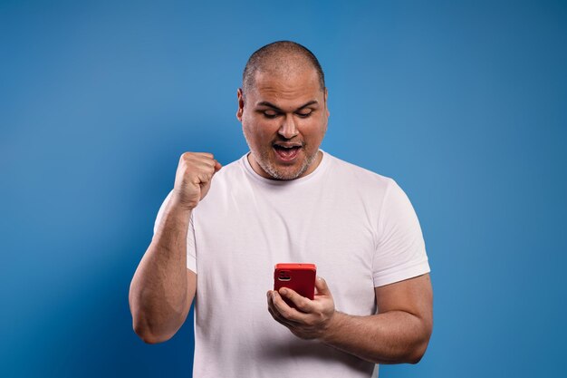 Photo man holding cell phone looking at it and celebrating