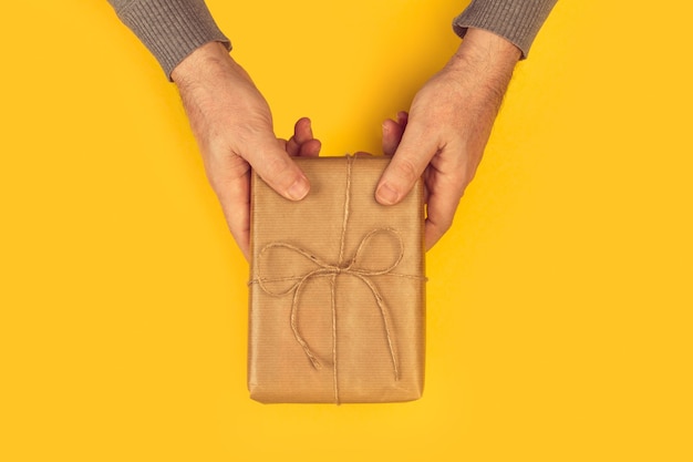 Man holding a christmas gift on a wooden table in a top view