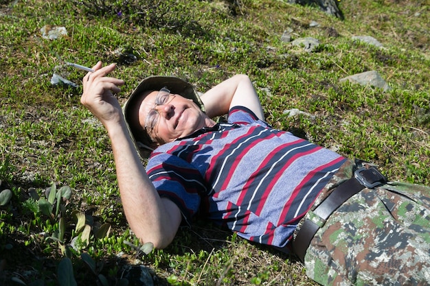 Man holding cigarette while lying on grass