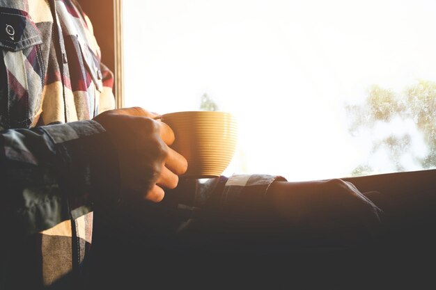 Photo man holding coffee cup by window