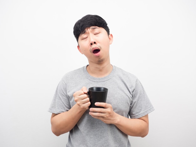 Man holding coffee feeling sleepy gesture yawn white background