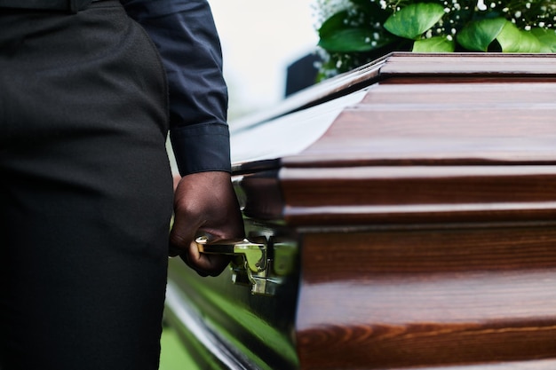 Man holding coffin by one of several handles while carrying it with other people