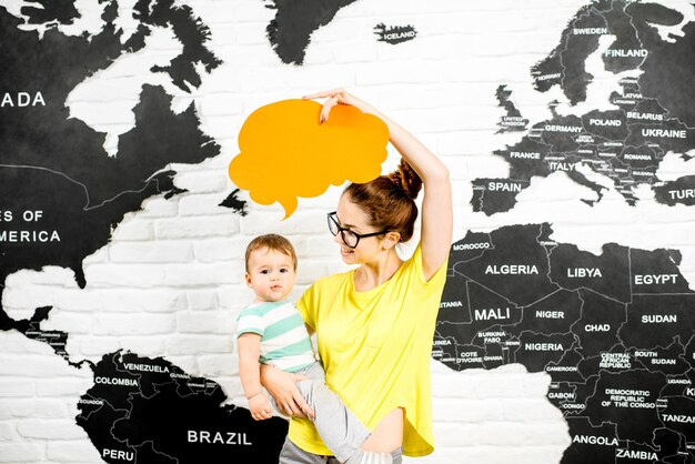 Photo man holding a colorful bubble above the head sitting at the office with world map on the background dreaming about traveling