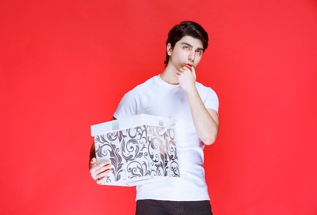 Man holding a colorful gift box and thinking.