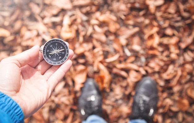 Man holding compass in autumn forest.