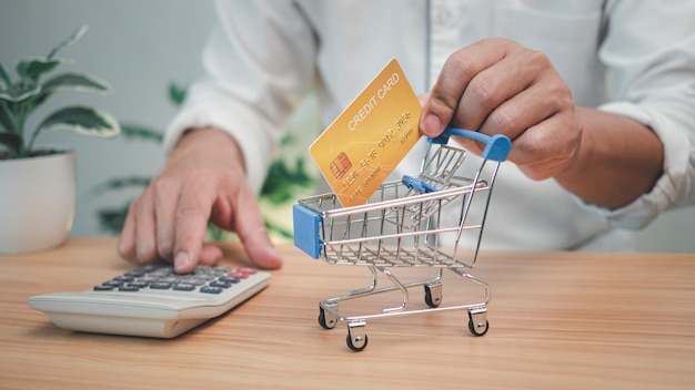 Man holding a credit card and pressing a calculator Shopping concept Cashless payment concept