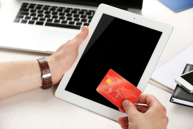 Man holding credit card and tablet on workplace background