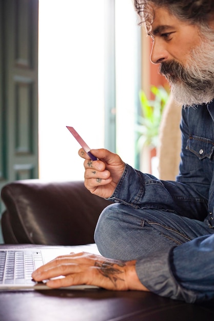 Man holding credit card and using laptop Businessman who works at home Online shopping ecommerce internet banking spending money work from home concept