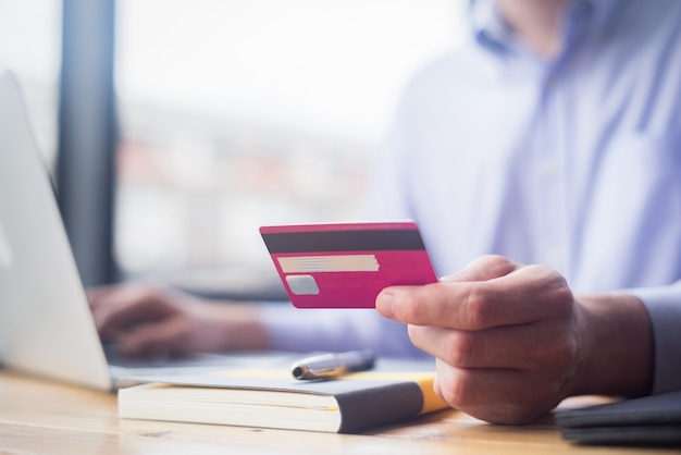 man holding credit card and using laptop and smartphone shopping website online