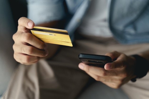 Uomo che tiene la carta di credito e utilizza lo smartphone per lo shopping online e-commerce bancario su internet