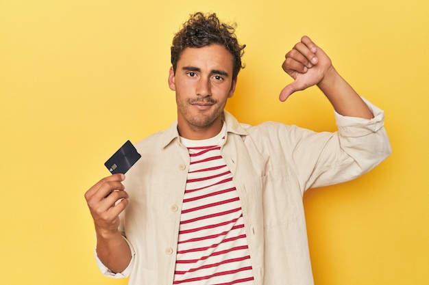 Man holding credit card on yellow showing a dislike gesture thumbs down Disagreement concept