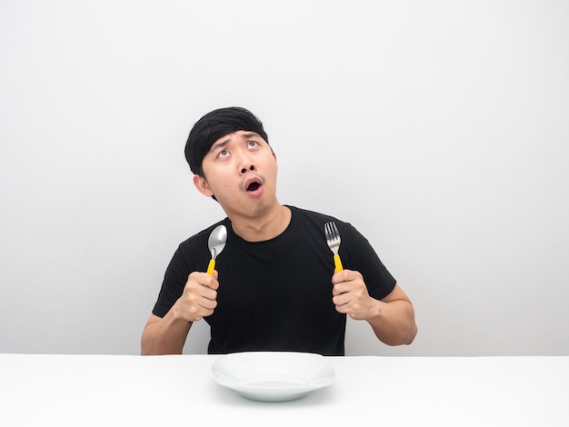 Man holding cutlery feeling hungry and looking up at copy space amazed emotion