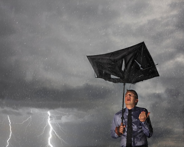 Фото Человек с поврежденным зонтиком, стоящий в сезон дождей