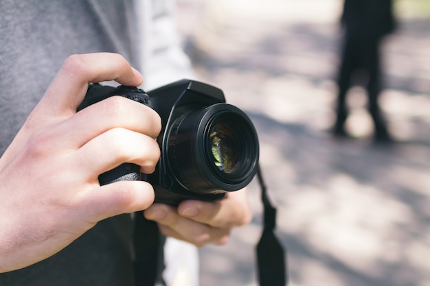 Man holding a digital photo camera, outdoor daylight