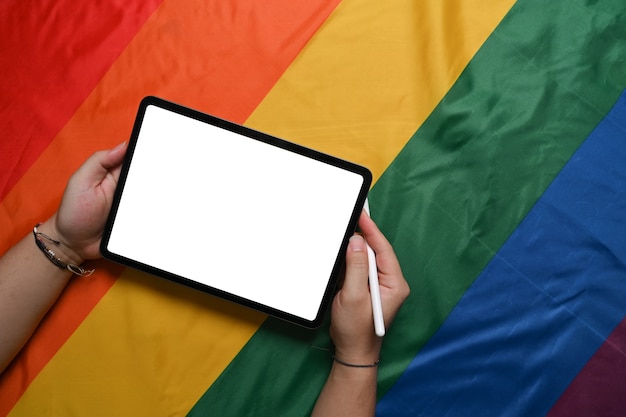 Uomo con tavoletta digitale su bandiera arcobaleno colorato. lgbt.