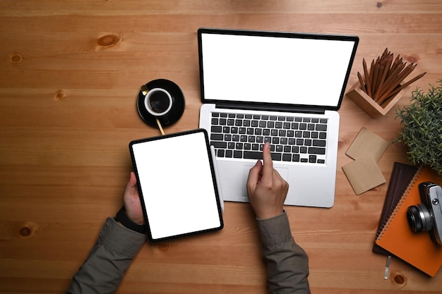 Man holding digital tablet and laptop computer on wooden table