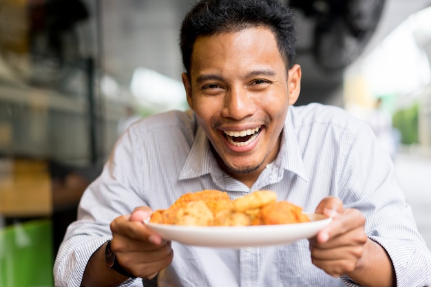 Мужчина держит блюдо из жареной курицы со счастливым