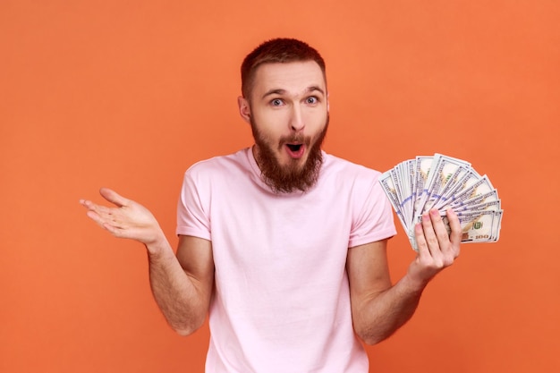 Man holding dollar banknotes and looking with amazed expression financial savings