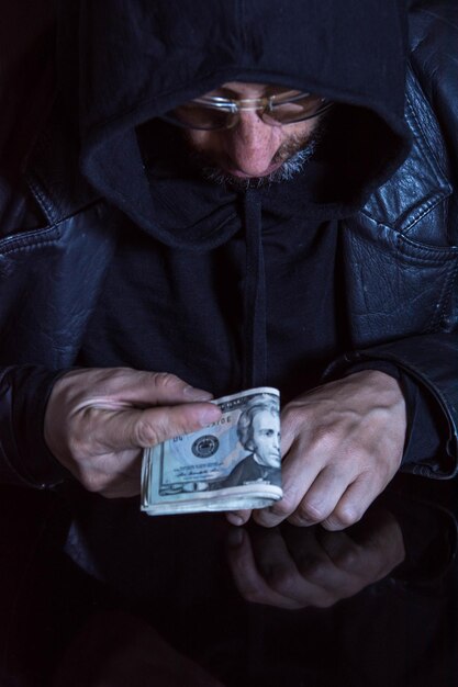 Man holding dollars bills trying to make a payment isolated on black background