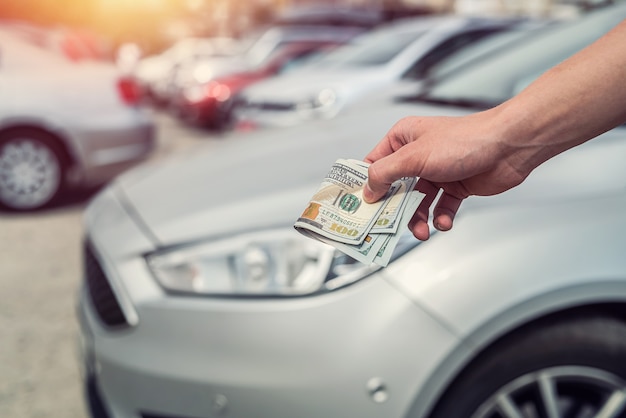 Man holding dollars for rent or buy car. success deal concept