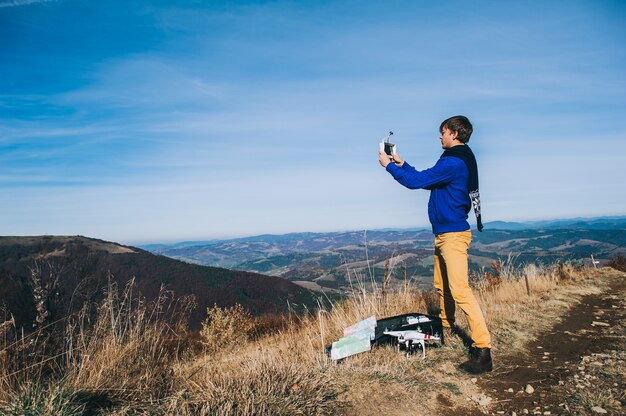 Uomo in possesso di un drone per la fotografia aerea. silhouette contro il cielo di tramonto